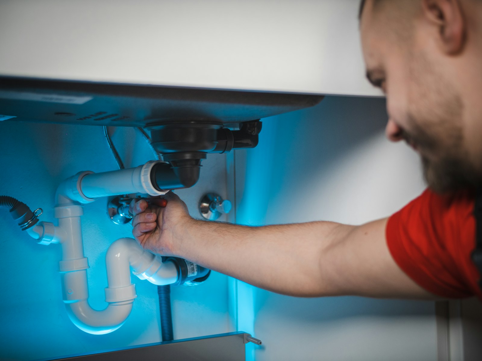 Installateur sanitaire ADM r\u00e9parant un siphon de lavabo